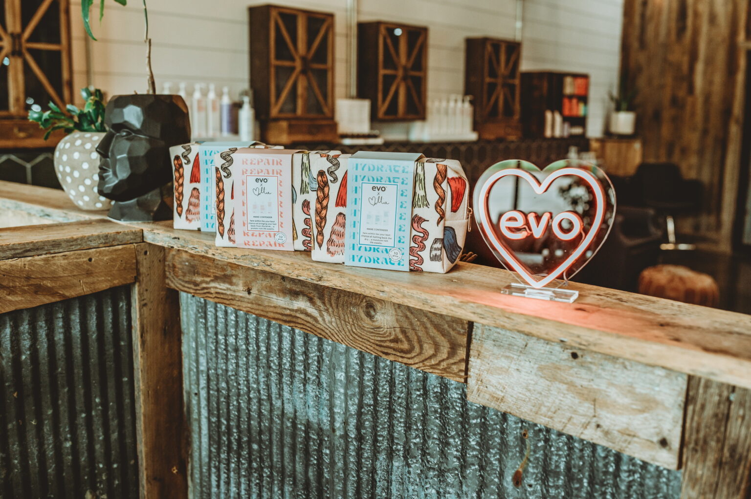 Reclaimed-wood front desk with EVO hair care products at The Refinery Hair Lounge
